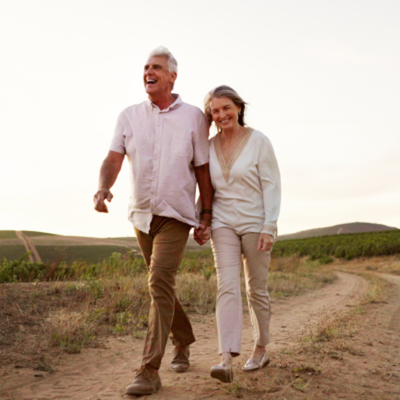 Senior couple holding hands while enjoying a walk together in the countryside.