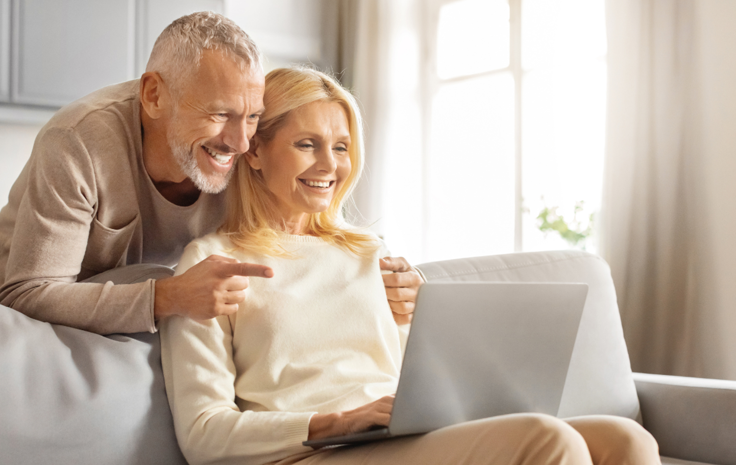 A couple looking at their laptop together, smiling