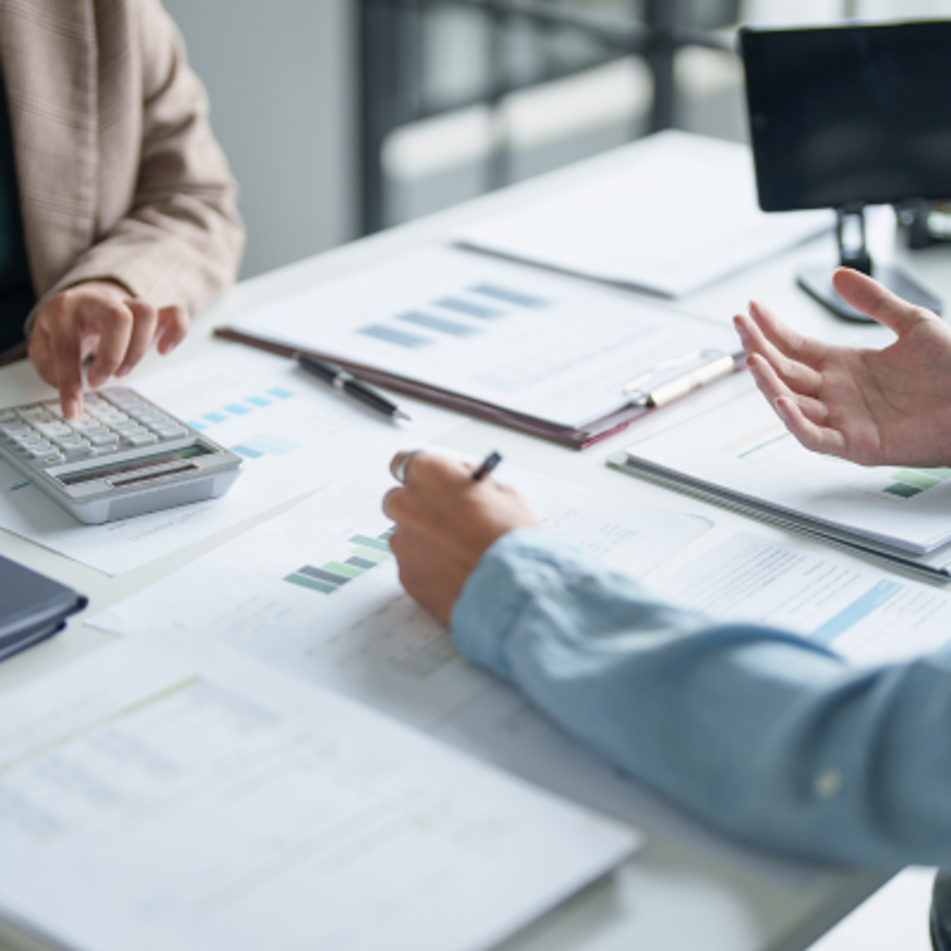 Two people working across from each other over a desk of paperwork