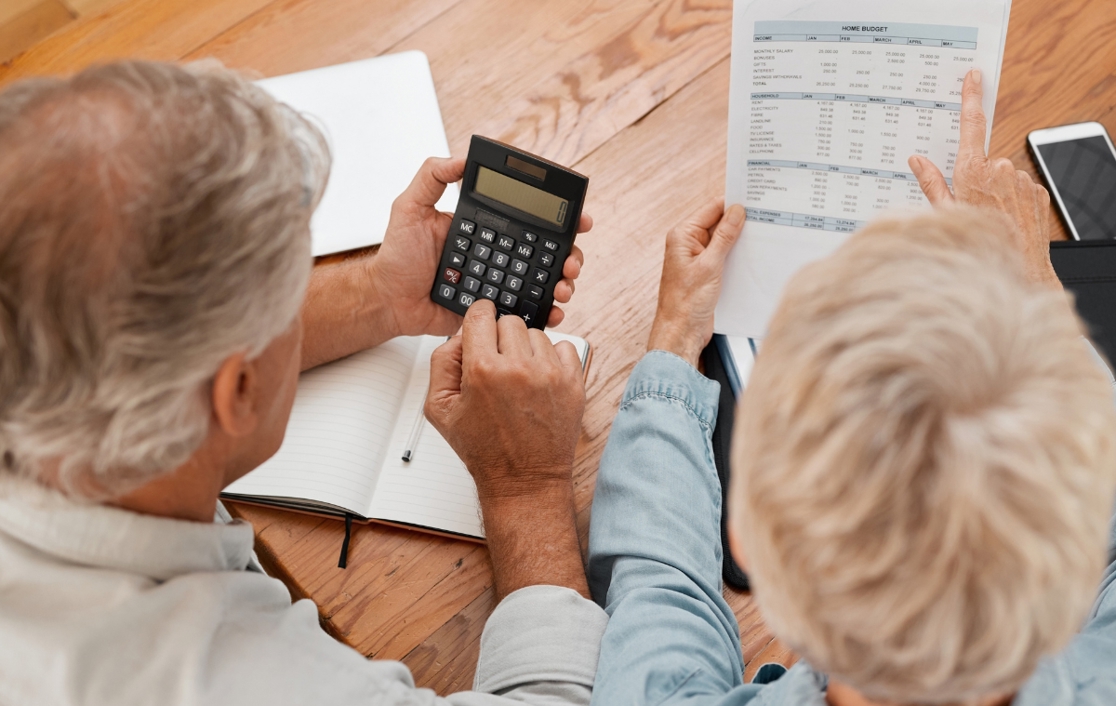 A senior couple with a calculator looking through their finances
